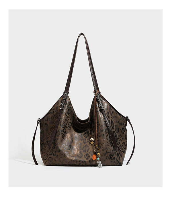 Slouchy leopard-print shoulder tote bag in tan and brown with long double straps, side tie straps, and dangling charm, detail