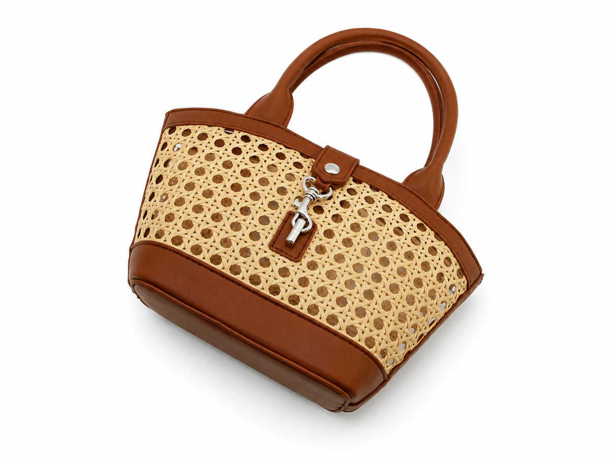 Structured mini tote bag with open-weave rattan body, leather-look arched handles and trim, front tab turn-lock closure, and