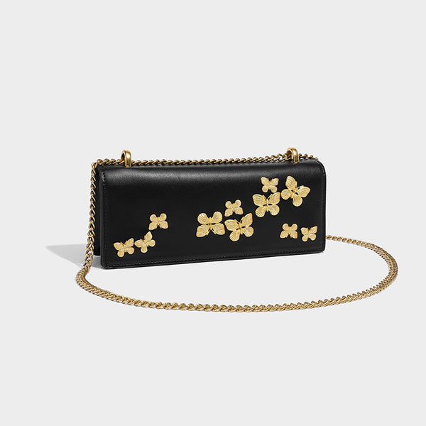 Slim rectangular crossbody bag with gold-tone butterfly metal appliqués and fine antiqued chain strap, front view