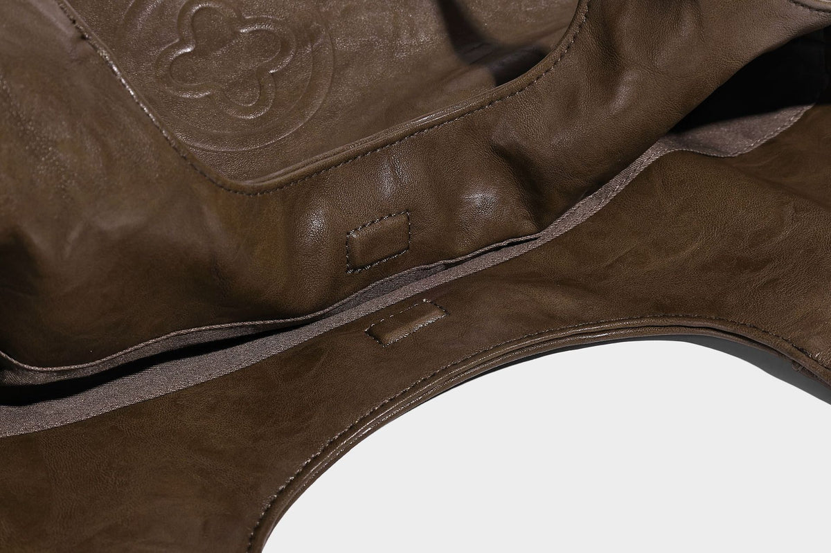 Large open-top tote bag with crinkled leather-look finish, long double shoulder straps, and embossed circular detail on