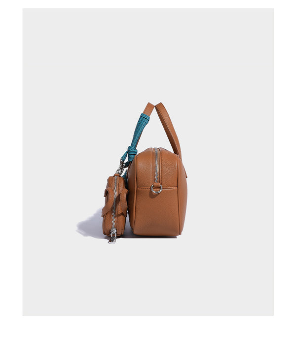Structured pebbled leather-look Boston bowling bag in tan with blue detachable round mini pouch, dual top handles, and