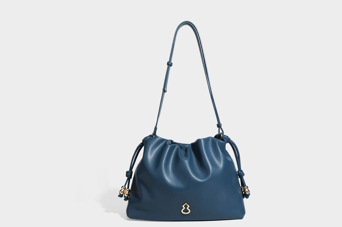 Slouchy ruched drawstring shoulder bag in smooth leather-look finish with gold-tone emblem and slim adjustable strap, detail