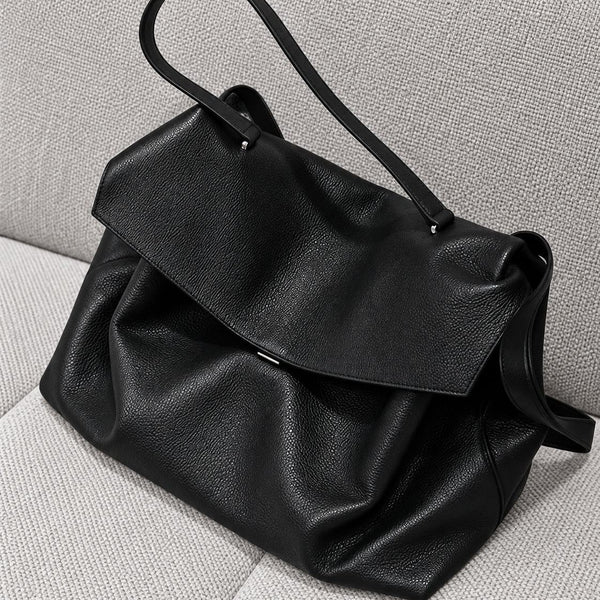 Large black slouchy leather-look shoulder bag with V-shaped envelope flap, silver-tone clasp, and adjustable strap, detail