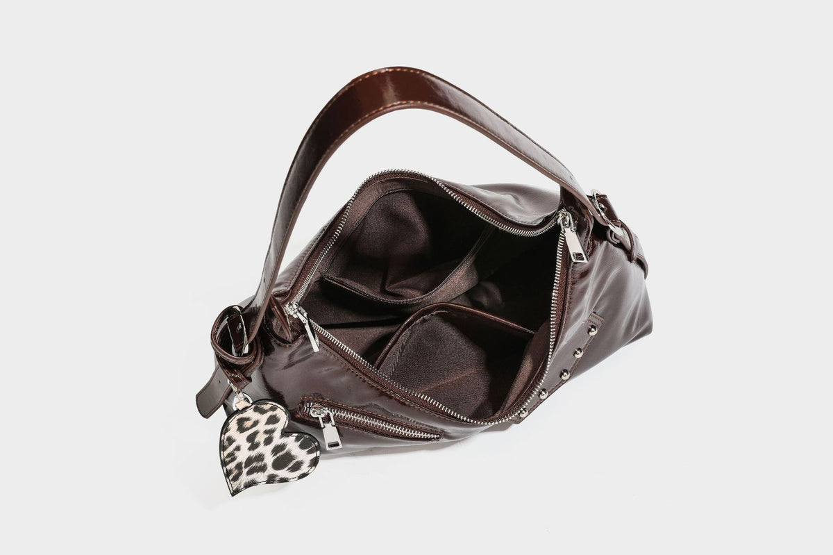Glossy dark brown hobo shoulder bag with slim strap, front zip pocket, stud detail, and detachable leopard-print heart charm