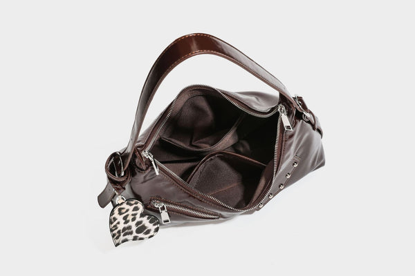 Glossy dark brown hobo shoulder bag with slim strap, front zip pocket, stud detail, and detachable leopard-print heart charm