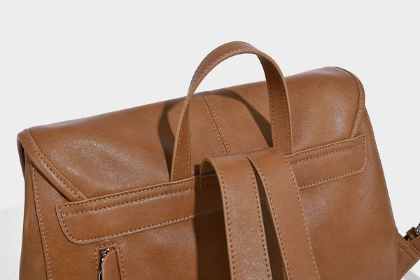 Structured tan leather-look flap backpack handbag with top handle, silver buckle hardware, and fold-over front closure