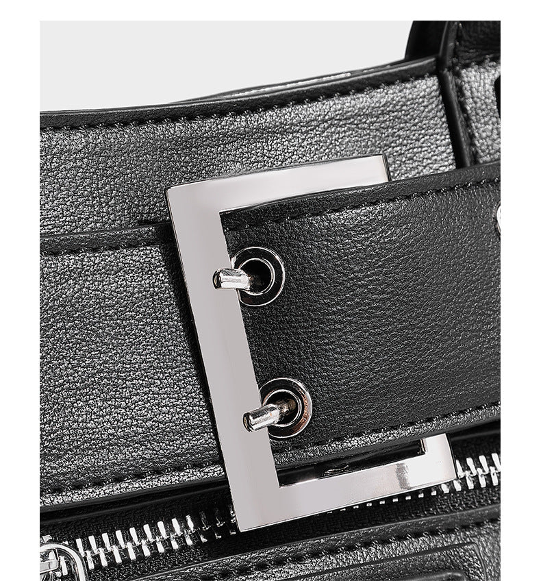 Black structured rectangular satchel bag with silver-tone rivets, large front buckle strap, zip pockets, dual top handles