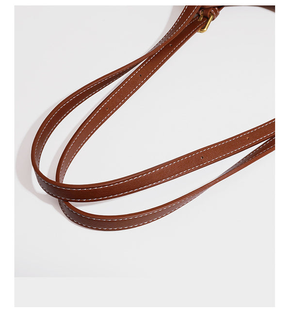 Structured smooth leather-look tote bag with long shoulder strap, gold-tone hardware, and hanging tassel-coin charm, detail