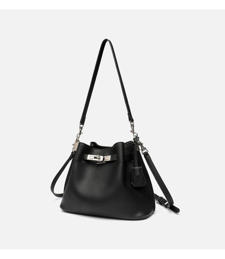 Soft-structured pebbled leather-look bucket bag with silver turn-lock front clasp and adjustable crossbody strap, detail view