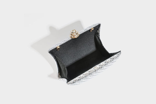 Small structured rectangular metallic woven-texture clutch bag with jeweled knob clasp and gold-tone chain strap, detail view