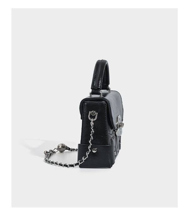 Kleine strukturierte Box-Tasche aus herzförmig gestepptem PU mit Henkel, silberfarbenem Kettenriemen zum Tragen als Crossbody und ovalem Drehverschluss, Detailansicht