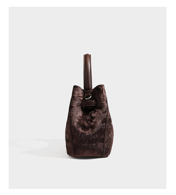 Small structured bucket satchel in embossed velvet-texture fabric with silver turn-lock hardware, rounded top handle, and