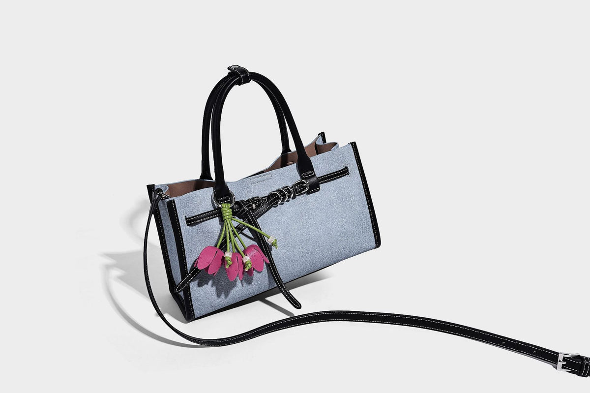 Structured rectangular tote satchel in denim-look fabric with dark trim, knotted front strap hardware, and detachable, detail