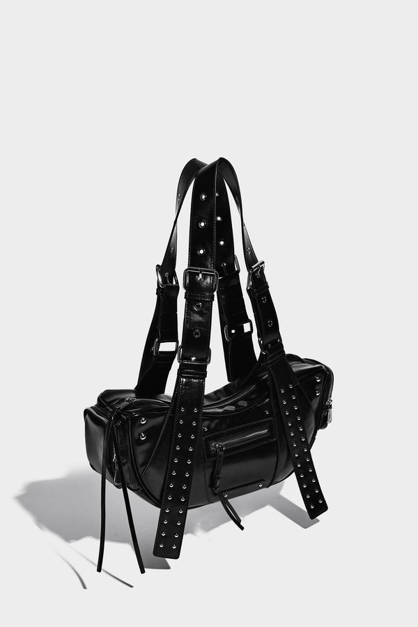 Glossy black crescent shoulder bag with silver-tone rivets, multiple zip pockets, and long adjustable studded straps, detail