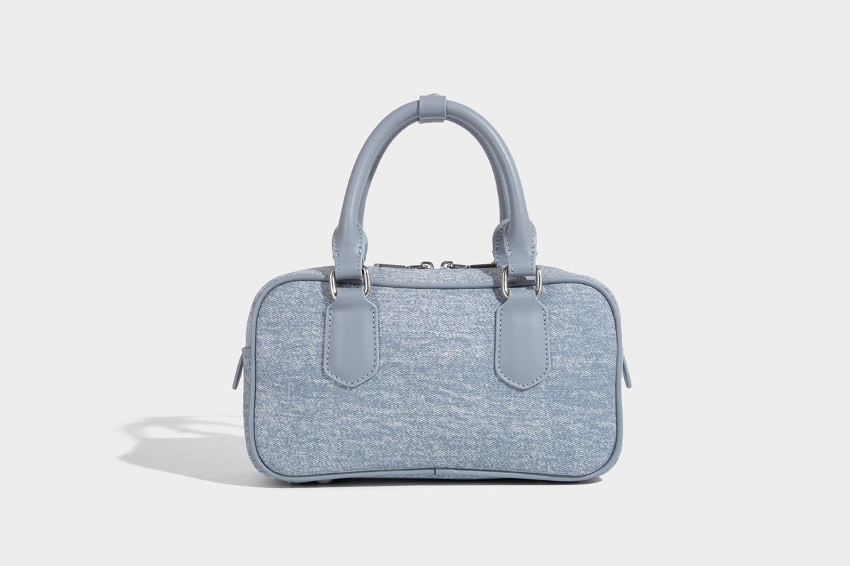 Small light blue denim-look barrel bag with white floral bead embroidery, dual top handles, and detachable shoulder strap