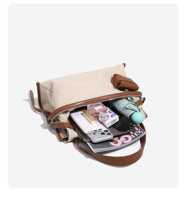 Cream canvas messenger shoulder bag with tan leather-look trim, dual zippers, tassel pulls, and attached mini front pouch