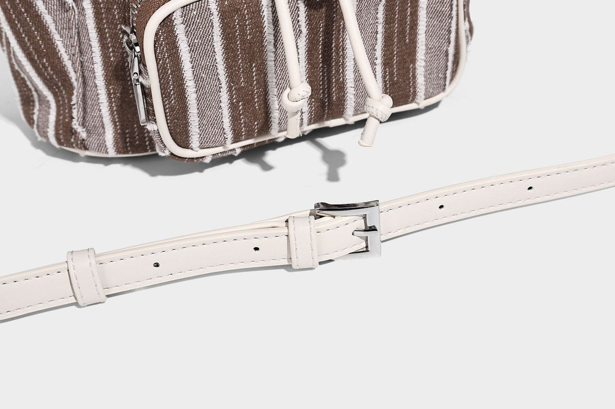 Weicher Rucksack aus gewebtem Material mit vertikalen Streifen, Überschlag, Kordelzug, vorderer Reißverschlusstasche, weißen Besätzen und Trägern in Lederoptik, Detailansicht