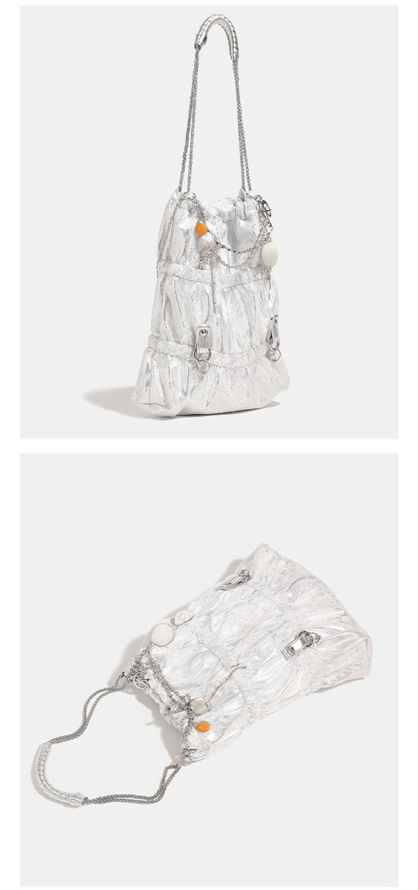 Slouchy lace-texture bucket bag with silver-tone chain strap, draped chain hardware, and shell charms, detail view 11