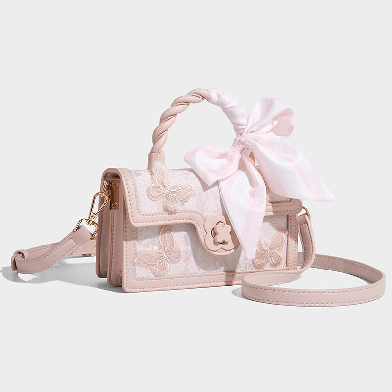 Small structured white flap bag with butterfly embroidery, flower-shaped turn-lock clasp, braided top handle with scarf bow
