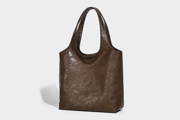 Large open-top tote bag with crinkled leather-look finish, long double shoulder straps, and embossed circular detail on