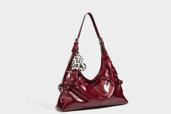 Glänzende dunkelbraune, lässig geschnittene Hobo-Schultertasche mit Riemendetail mit silberfarbenen Ösen, Reißverschlussfach auf der Vorderseite und Herz mit Leopardenmuster