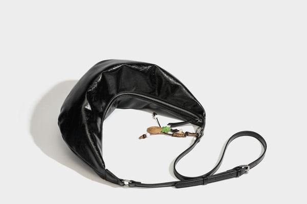 Legere, halbmondförmige Hobo-Schultertasche in glänzender, geknautschter Lederoptik mit schmalem Riemen, Ringbeschlägen in Silberoptik und