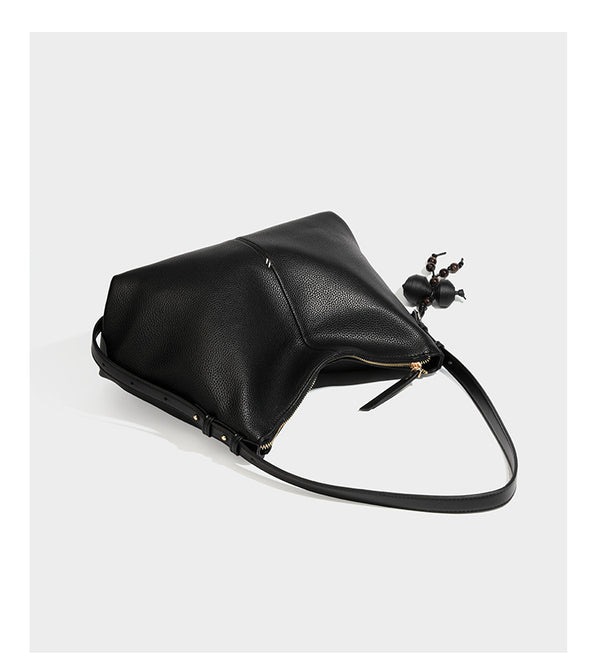 Slouchy hobo shoulder bag with pebbled leather-look finish, zip-top closure, gold-tone hardware, and hanging bead charm