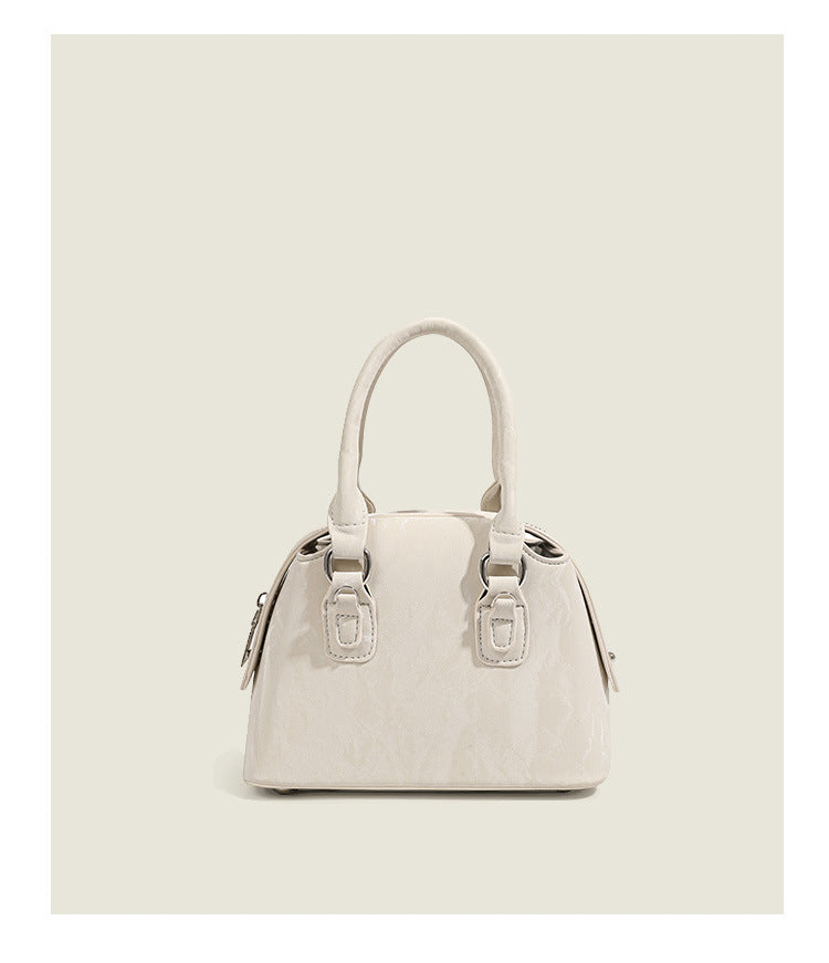 Small structured Boston bag in cream with glossy crinkled finish, sheer bow accent, silver-tone hardware, dual top handles