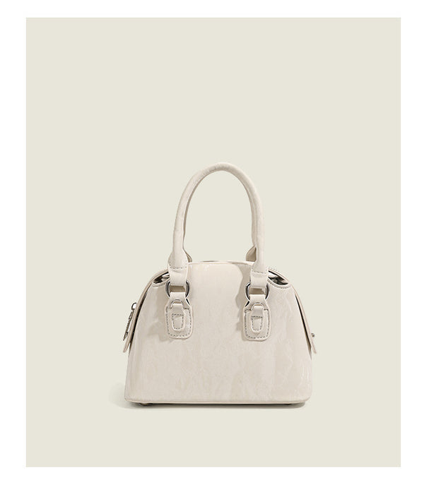 Small structured Boston bag in cream with glossy crinkled finish, sheer bow accent, silver-tone hardware, dual top handles
