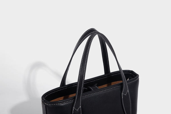 Compact structured bucket tote bag with pebbled textured finish, dual top handles, silver-tone lock hardware, and detachable
