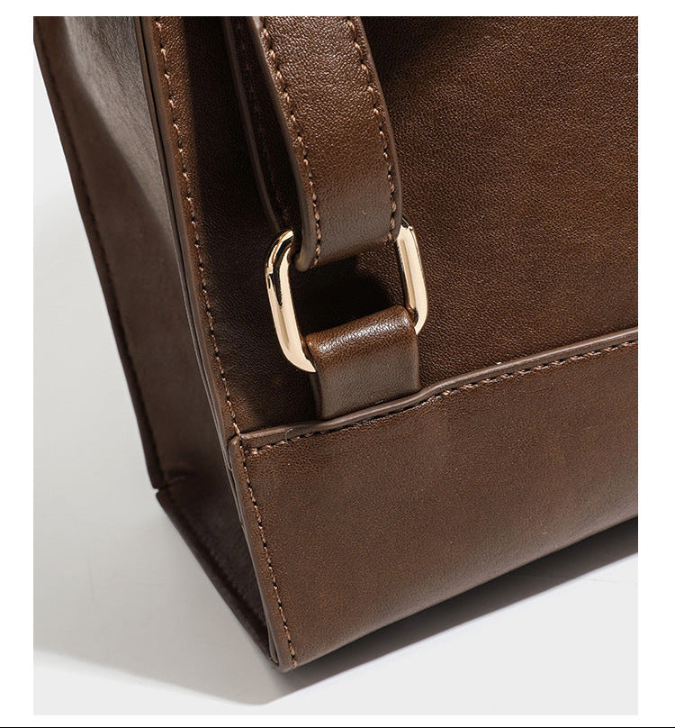Structured suede-look convertible backpack handbag with flap closure and gold-tone emblem hardware in chocolate brown, detail