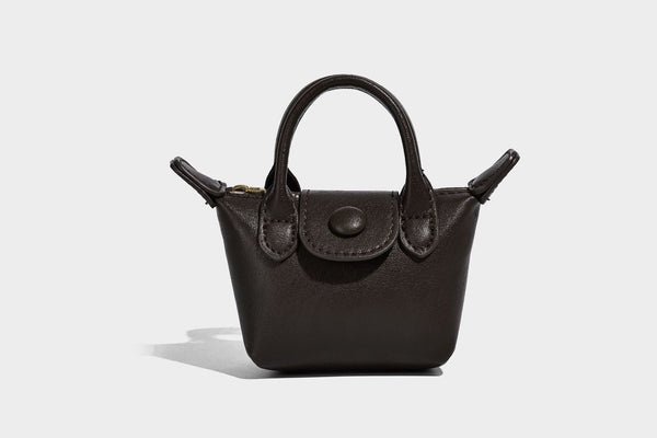 Strukturierte Tote-Bag mit gewebter Oberfläche, befestigtem Mini-Charm-Täschchen, geknoteten Tragegriffen und abnehmbarem Schulterriemen, Detailansicht