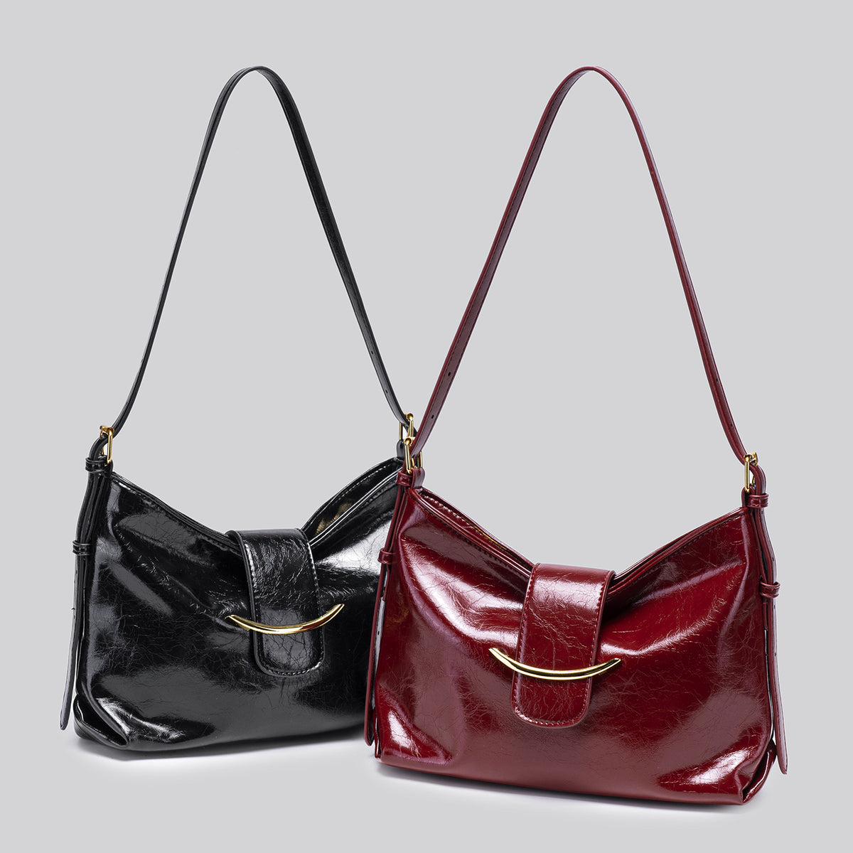 Glossy burgundy leather-look shoulder bag with curved gold-tone bar front closure, crinkled oil-wax texture, and adjustable