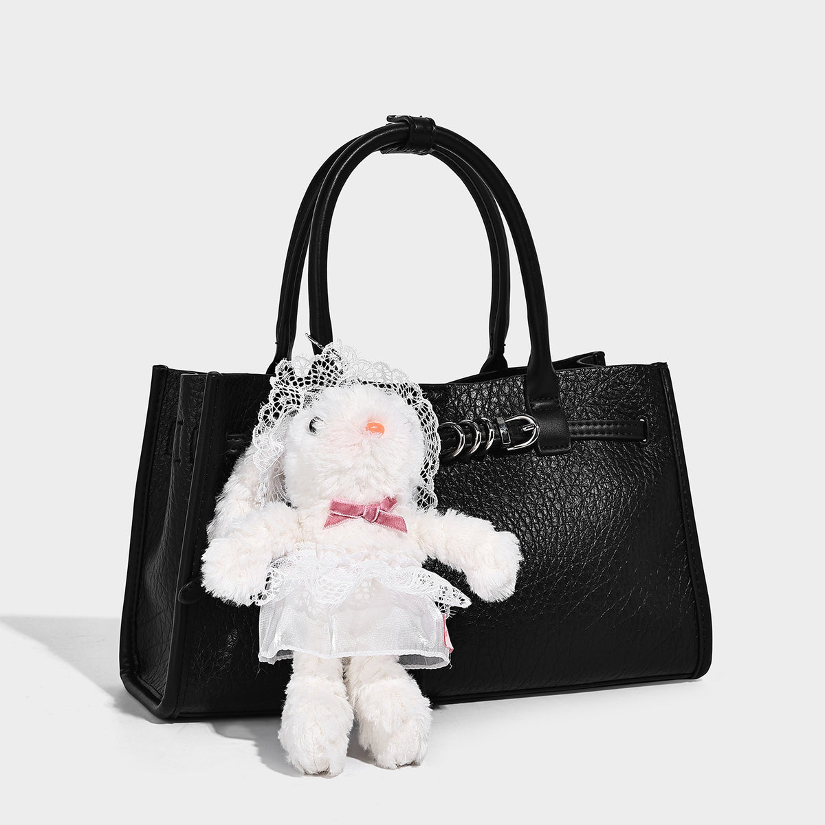 Structured trapezoid tote bag in pebbled leather-look finish with double top handles, silver-tone bar hardware, and, detail