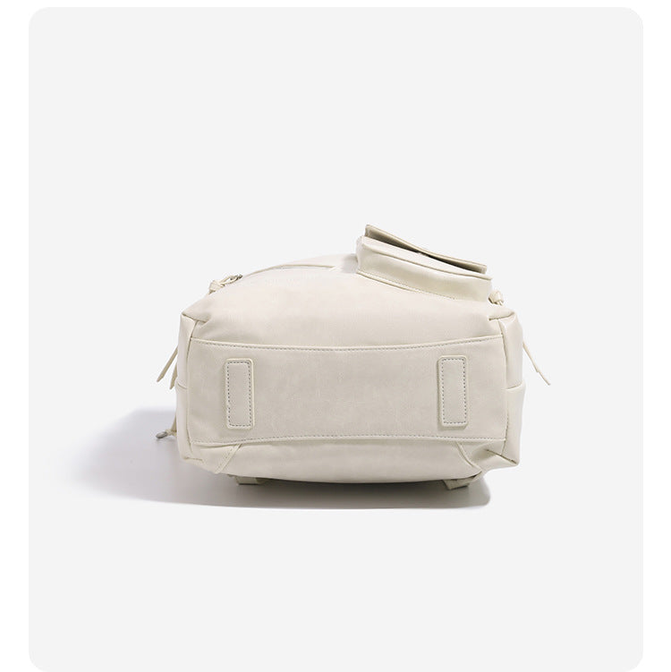 Structured smooth leather-look backpack handbag with dual top zip closure, diagonal front zip pocket, snap-flap mini pocket