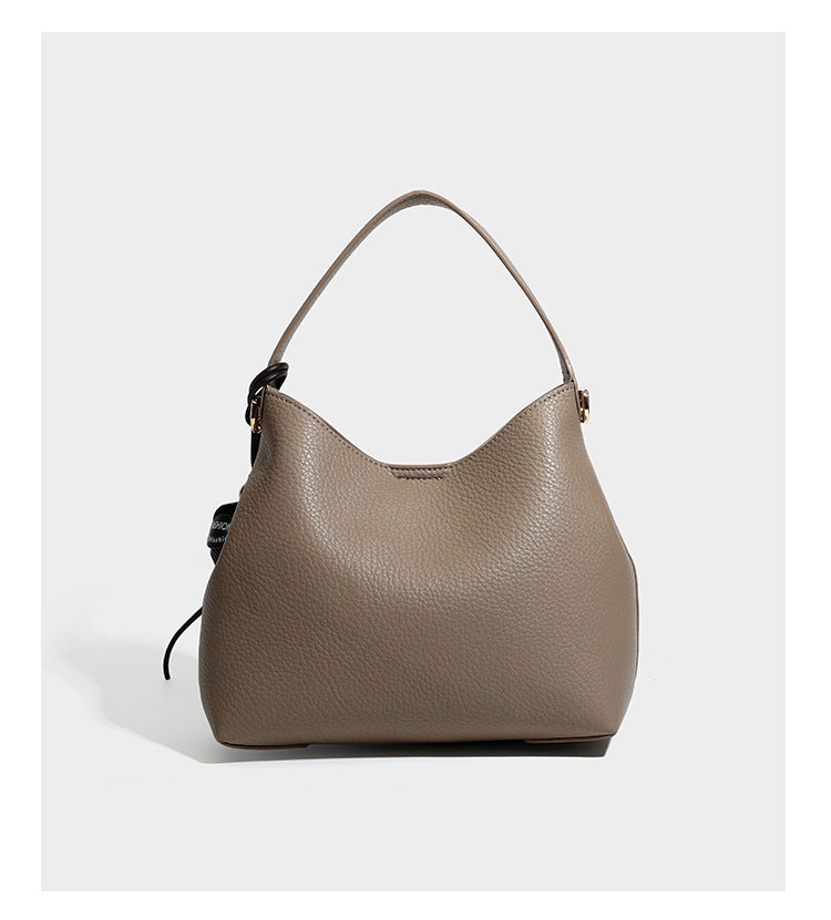 Hobo-Schultertasche in genarbtem Lederlook mit goldfarbener Kette als Schulterriemen, kurzem Tragegriff und dekorativem seitlichem Anhänger, Detailansicht