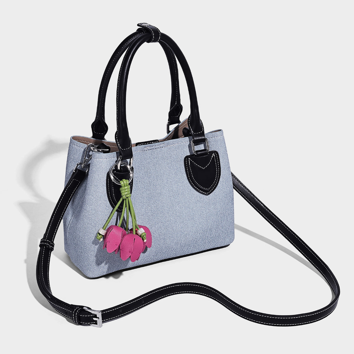 Structured light-blue denim-look tote bag with black leather-look handles, white contrast stitching, silver-tone hardware