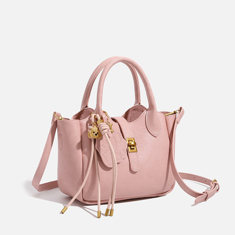 Small structured pebbled leather-look mini tote bag with gold-tone hardware, front toggle closure, knotted bear tassel charm