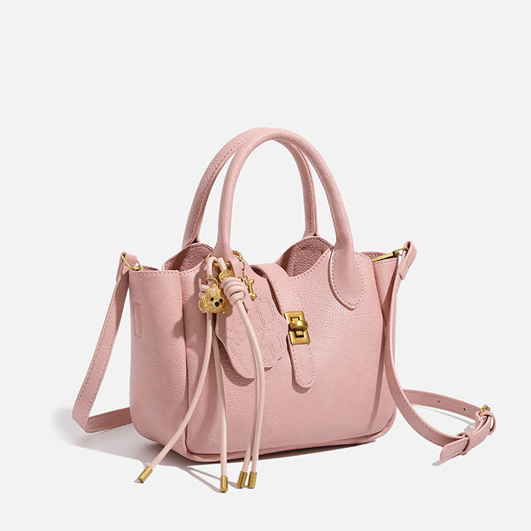Small structured pebbled leather-look mini tote bag with gold-tone hardware, front toggle closure, knotted bear tassel charm