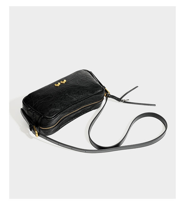 Compact black crinkled leather-look baguette shoulder bag with gold-tone arch hardware and adjustable strap, detail view 13