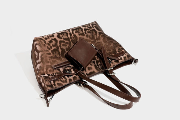 Glossy leopard-print tote bag with leather-look dark trim, dual top handles, detachable shoulder strap, and attached front