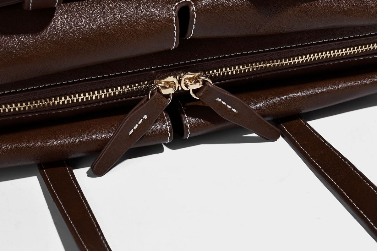 Strukturierte rechteckige Baguette-Schultertasche aus dunkelbraunem Material in glatter Lederoptik mit zwei Riemen und Reißverschluss oben