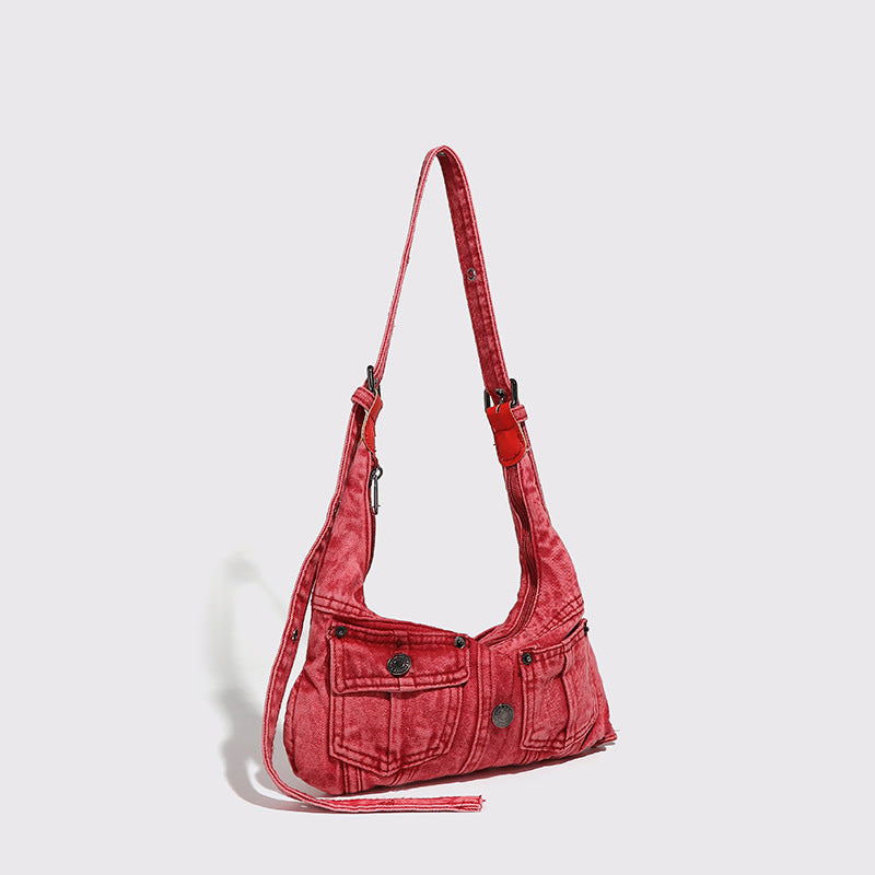 Compact washed red distressed-textile shoulder bag with front flap pockets, dark metal hardware, and long adjustable strap