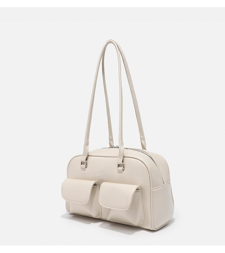 Structured glossy leather-look bowling shoulder bag with two front flap pockets, top zip closure, and long double shoulder