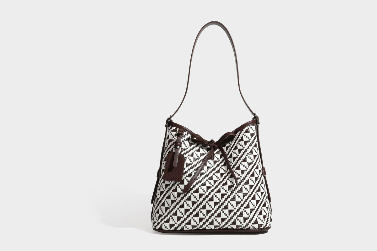 Woven geometric bucket shoulder bag in white and dark brown two-tone pattern with leather-look trim and drawstring top