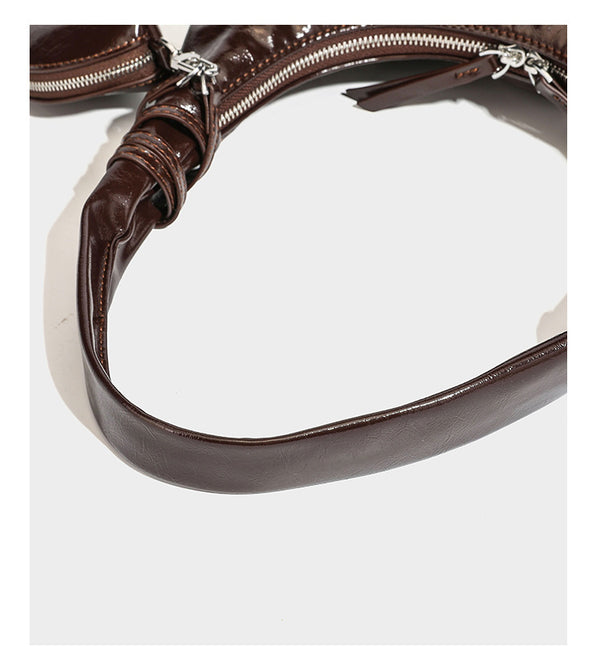 Lässige Hobo-Schultertasche in glänzender Lederoptik mit silbernen Schnürösen und einer Schleife aus Ripsband auf der Vorderseite, Detail