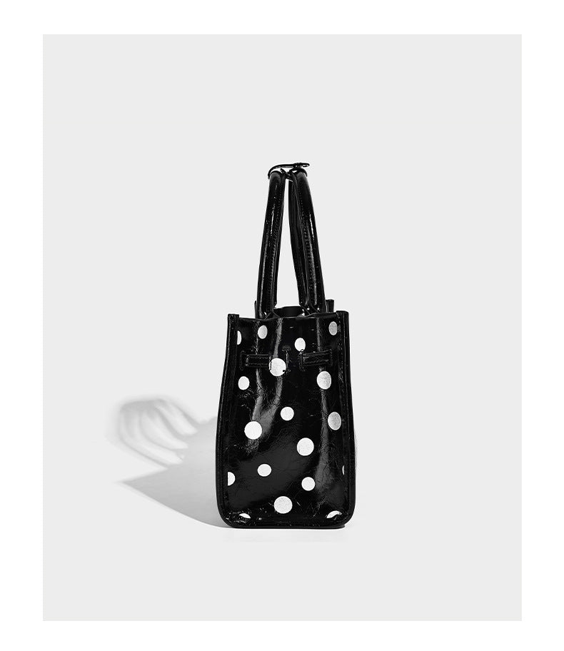 Structured glossy polka-dot tote bag with double top handles and front buckle hardware, detail view 9
