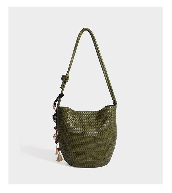 Olive green woven leather-look bucket bag with braided crossbody strap, knotted adjustment, and gold-tone tassel charm with
