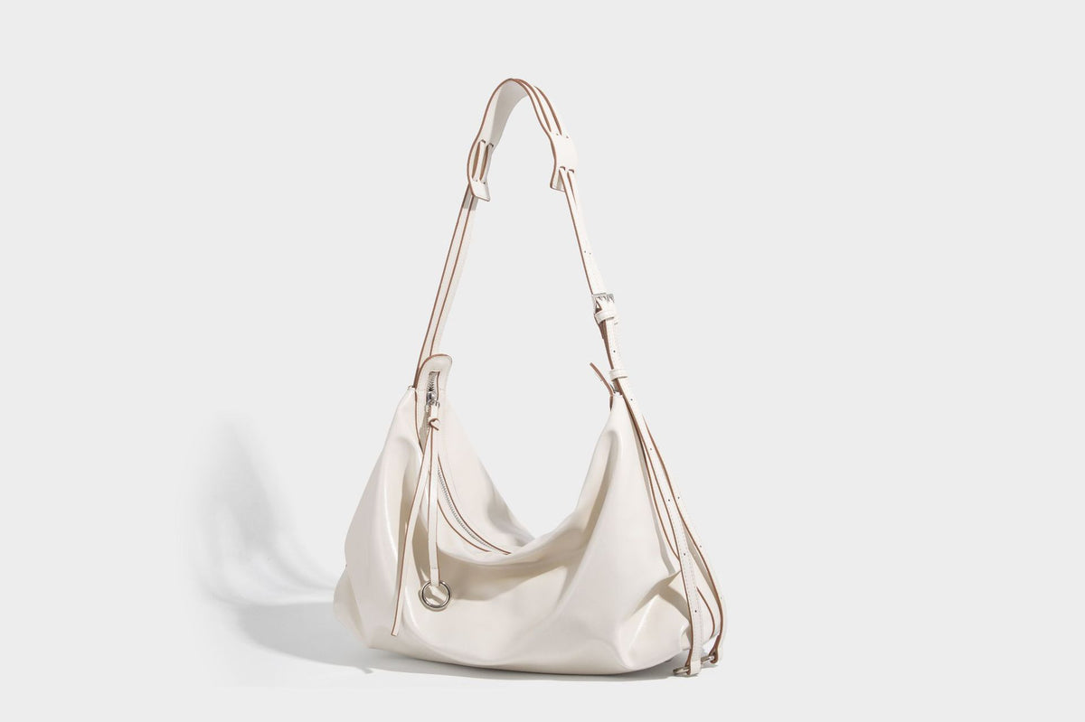 Glossy black slouchy hobo shoulder bag with zip closure, silver-tone ring hardware, and adjustable crossbody strap, detail