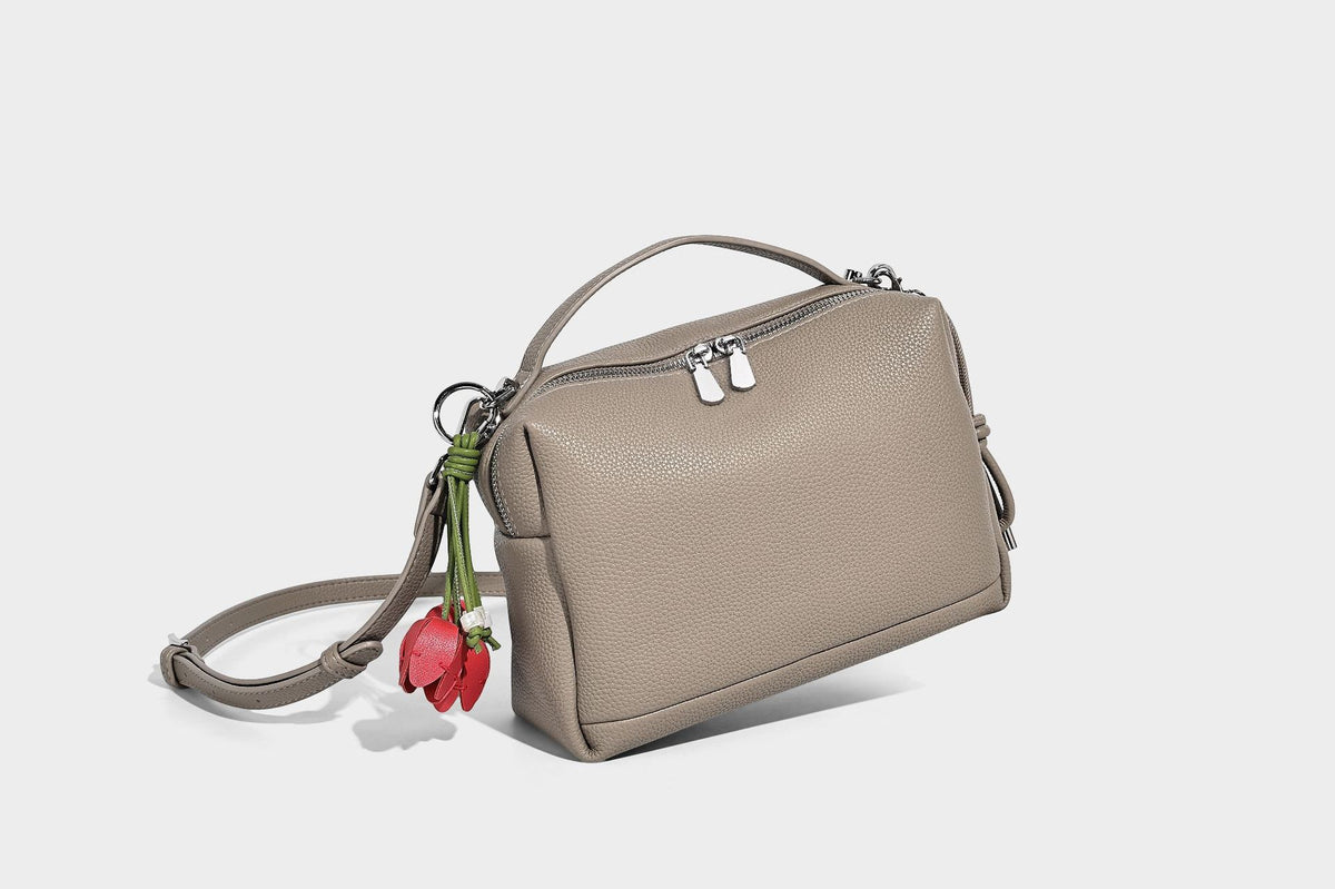 Kleine strukturierte Crossbody-Tasche mit Tragegriff aus genarbtem Material, Reißverschluss, silberfarbenen Beschlägen und optionalem Quastenanhänger